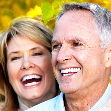 The image shows two individuals, an older man and woman, smiling at each other.